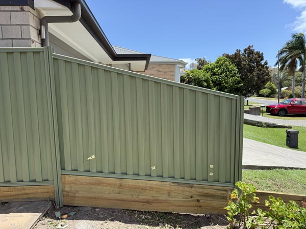 A raked Colorbond fence panel with treated pine sleepers