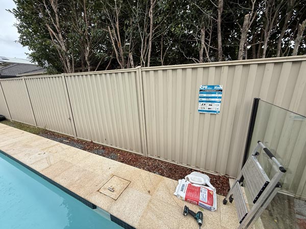 Colorbond fence panels in Wavelok sheet profile and Domain Primrose colour also acting as pool barrier