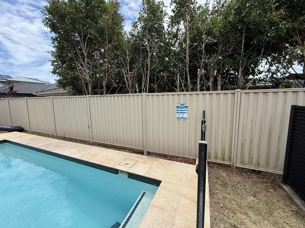 Colorbond fence panels in Wavelok sheet profile and Domain Primrose colour also acting as pool barrier